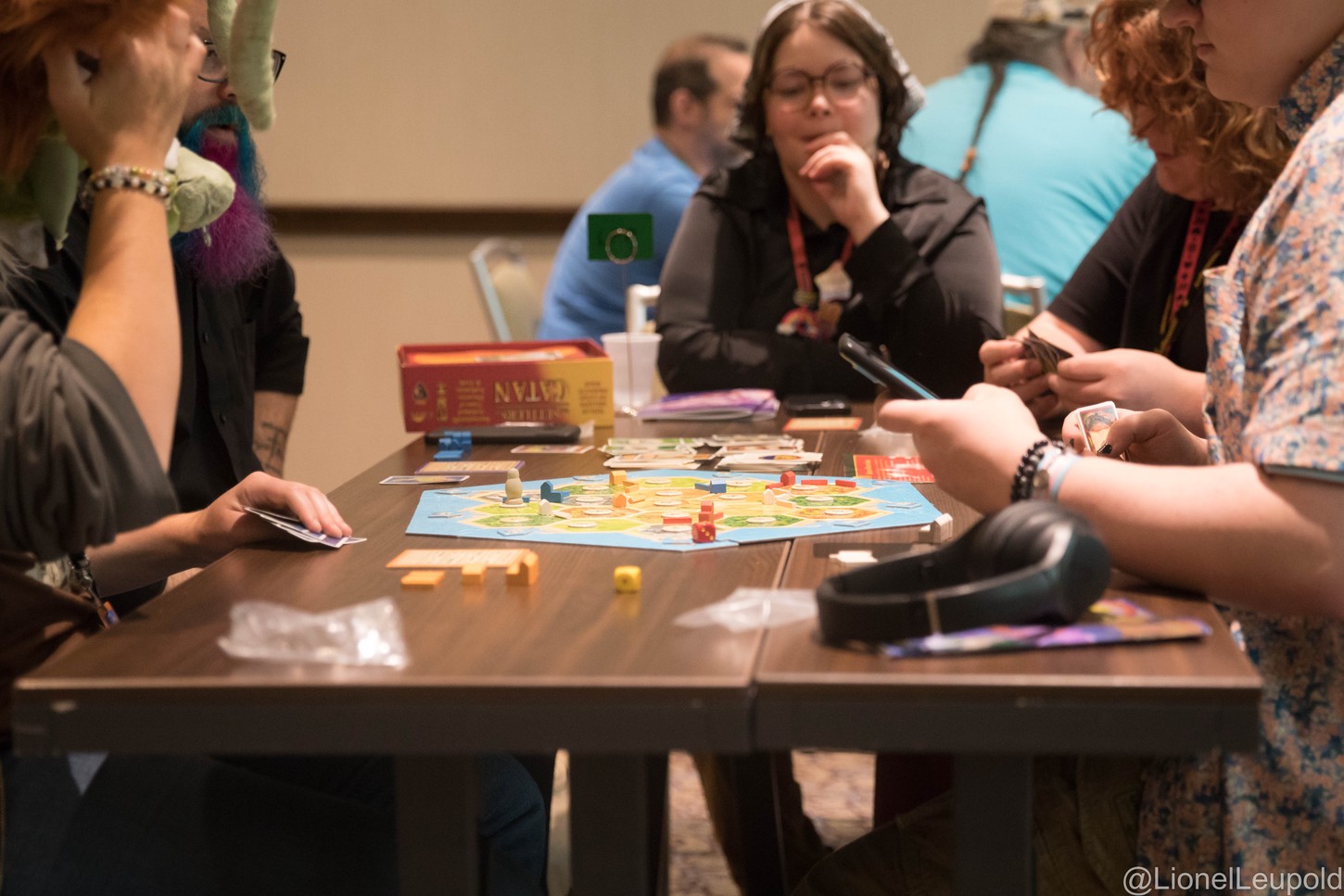 A photograph of multiple people playing a game of Settlers of Catan.